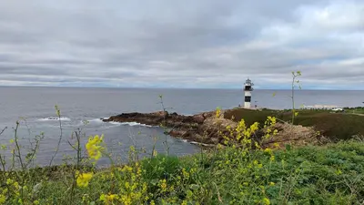 a lighthouse sitting on top of a hill next to the ocean at O meo refuxio in Barreiros
