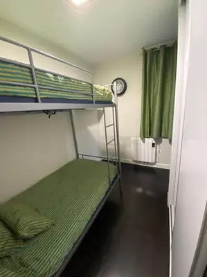 a bunk bed in a small room with a green bed at Apartamento de playa familiar, piscina y garaje. in Ares