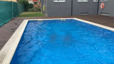 a large blue swimming pool on a wooden deck at Apartamento de playa familiar, piscina y garaje. in Ares