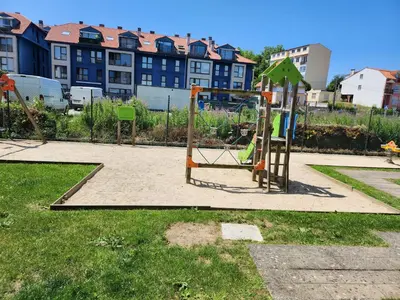 a playground with a swing set in a park at Apartamento de playa familiar, piscina y garaje. in Ares
