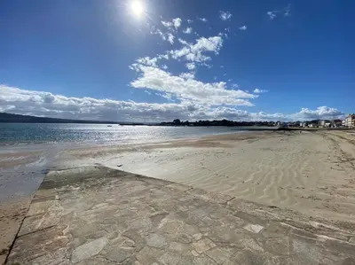 a sandy beach with the sun in the sky at Apartamento de playa familiar, piscina y garaje. in Ares