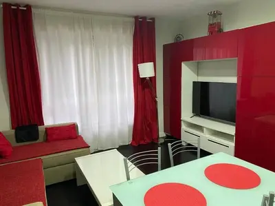a living room with red curtains and a television at Apartamento de playa familiar, piscina y garaje. in Ares