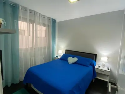 a bedroom with a blue bed and a window at Apartamento de playa familiar, piscina y garaje. in Ares