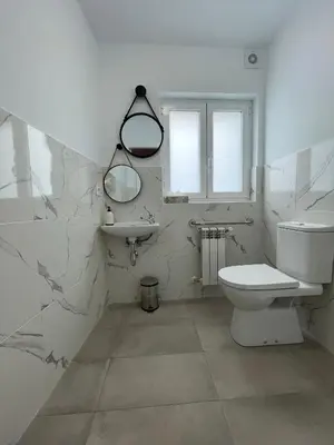 a white bathroom with a toilet and a sink at Apartamentos turísticos Praia de Seselle, terraza y jardín a un paso de la playa in Ares
