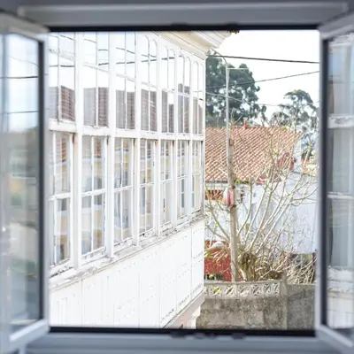 a window view of a white building with windows at Apartamentos turísticos Praia de Seselle, terraza y jardín a un paso de la playa in Ares