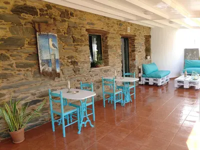 a room with tables and chairs and a stone wall at Apartamentos turísticos Praia de Seselle, terraza y jardín a un paso de la playa in Ares