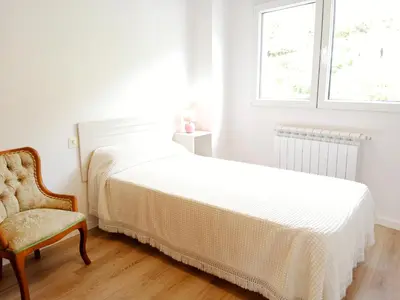 a bedroom with a bed and a chair and a window at Atico en La Ría in Vivero