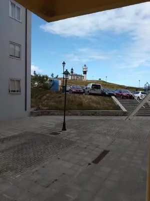 a street light in a parking lot next to a building at EnSAN CIPRIÁN Faro de Punta Atalaya in Cervo