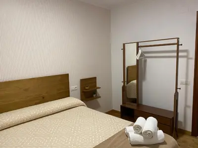 a bedroom with a bed and a mirror and towels at Pensión Casa Cancela in Palas de Rei