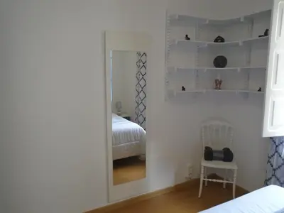 a mirror in a bedroom with a bed and a chair at Piso céntrico Pontedeume in Puentedeume