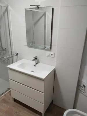 a white bathroom with a sink and a mirror at Piso céntrico Pontedeume in Puentedeume