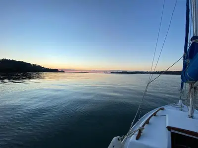 a boat on the water with the sunset in the background at O Cerrulo Apartamento céntrico Pontedeume in Puentedeume