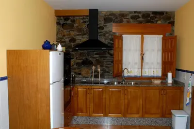 a kitchen with wooden cabinets and a white refrigerator at Casa Xuaquin in Moal
