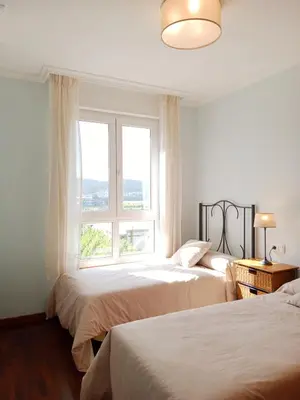 a white bedroom with two beds and a window at El Mirador 2 in Vivero