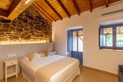 a bedroom with a bed and a stone wall at Alojamiento Turístico Caxide Parada de Sil Ribeira Sacra in Parada del Sil