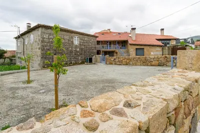a stone wall in front of a house at Alojamiento Turístico Caxide Parada de Sil Ribeira Sacra in Parada del Sil