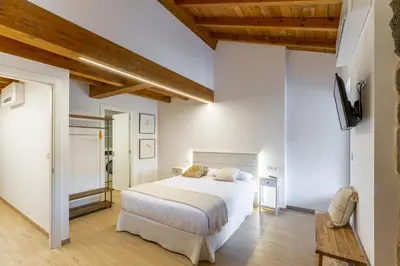 a bedroom with a large white bed and wooden ceilings at Alojamiento Turístico Caxide Parada de Sil Ribeira Sacra in Parada del Sil