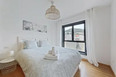 a white bedroom with a bed and a window at Apt. p/4 en la Playa de Viveiro in Viveiro