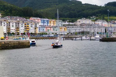 a boat in the water in a harbor with buildings at Apt. p/4 en la Playa de Viveiro in Viveiro