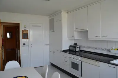 a white kitchen with white cabinets and a microwave at Acogedor piso con vistas en Sada in Sada