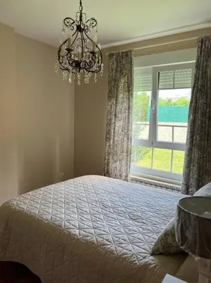 a bedroom with a bed with a chandelier and a window at Piso con jardín en Ribadeo in Ribadeo