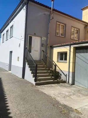 a house with a white door and stairs next to a garage at Casa Roque in Monforte de Lemos