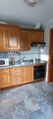 a kitchen with wooden cabinets and a sink at Apartamentos Rurales San Esteban de los Buitres - Illano in San Esteban