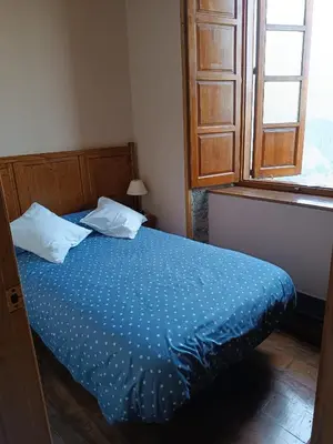 a bedroom with a bed with blue sheets and a window at Apartamentos Rurales San Esteban de los Buitres - Illano in San Esteban