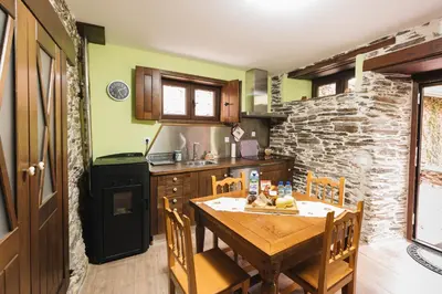 a kitchen with a wooden table and a stone wall at CASA TRISQUEL in Hospital