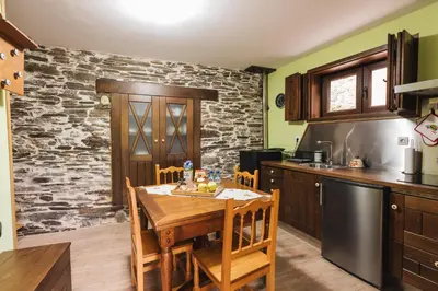 a kitchen with a wooden table and a stone wall at CASA TRISQUEL in Hospital