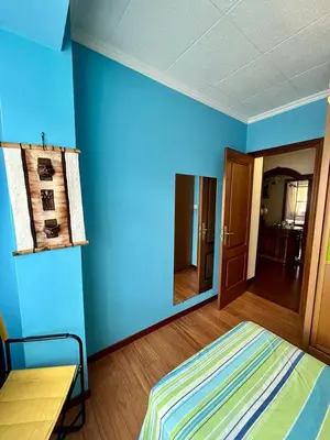 a blue room with a bed and a mirror at Piso en pleno centro de Miño izquierda in Miño
