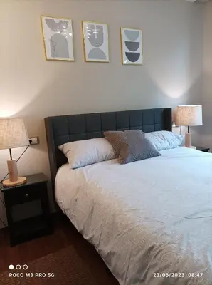 a bedroom with a bed with two lamps and pictures on the wall at Apartamento Piscina 2G by Urraca Suites Viveiro in Viveiro