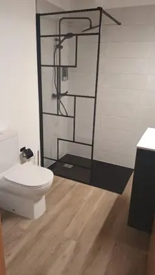 a bathroom with a toilet and a glass shower at Reginita Apartamentos in Arbo