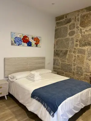 a bedroom with a bed with a stone wall at Reginita Apartamentos in Arbo