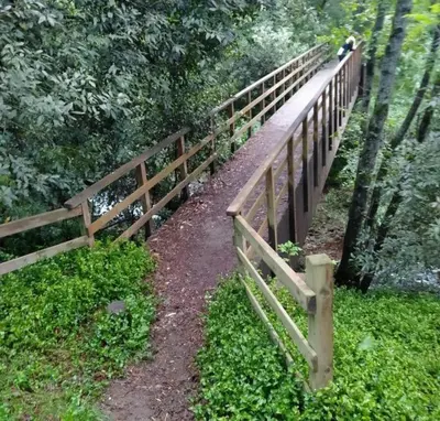a wooden fence on a dirt path next to trees at Reginita Apartamentos in Arbo
