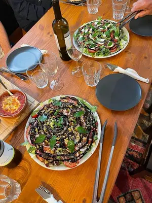two plates of food on a wooden table at Vagabond Vieiras Beds & Communal Dinner Included Albergue LE-210 in La Portela de Valcarce