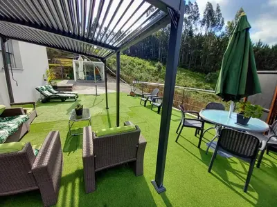 a patio with a table and chairs and an umbrella at Casa Rocha Velha con terraza y piscina particular in Santiago de Compostela