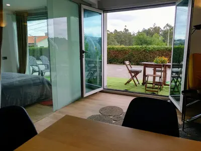 a room with a sliding glass door with a table and chairs at Casa Rocha Velha con terraza y piscina particular in Santiago de Compostela