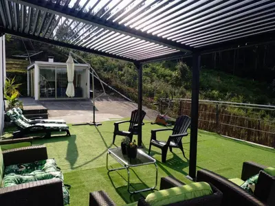 a patio with chairs and a pergola at Casa Rocha Velha con terraza y piscina particular in Santiago de Compostela
