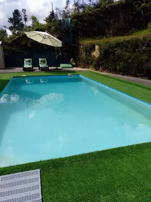 a large blue swimming pool with an umbrella at Casa Rocha Velha con terraza y piscina particular in Santiago de Compostela