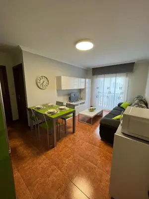 a kitchen and a living room with a table and a couch at Apartamento Marichu in Melide