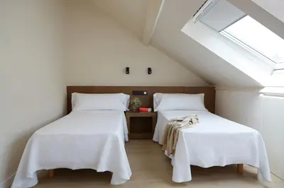 a room with two beds with white sheets and a window at Hotel Trina 20 in Palas de Rei