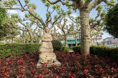 a statue of a woman in a garden with flowers at Arzúa Centro Vivienda de uso turístico in Arzúa