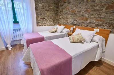 a room with two beds and a stone wall at Casa Choureiro Apartamentos Rurales in Navia