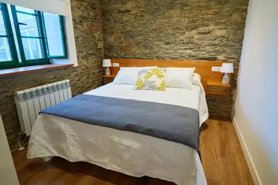 a bed in a room with a brick wall at Casa Choureiro Apartamentos Rurales in Navia