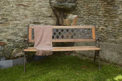 a blanket on a bench in front of a building at Casa Choureiro Apartamentos Rurales in Navia