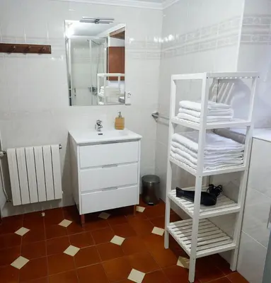 a bathroom with a white sink and a white shelf with towels at Casa Choureiro Apartamentos Rurales in Navia