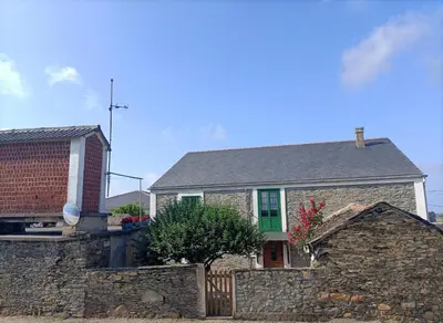 a stone house with a green door and a stone wall at Casa Choureiro Apartamentos Rurales in Navia