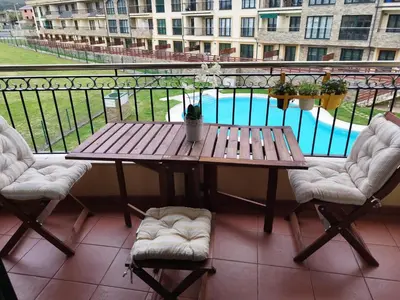 a wooden table and chairs on a balcony with a pool at COSTA REINANTE SPA Y PISCINA in San Miguel de Reinante