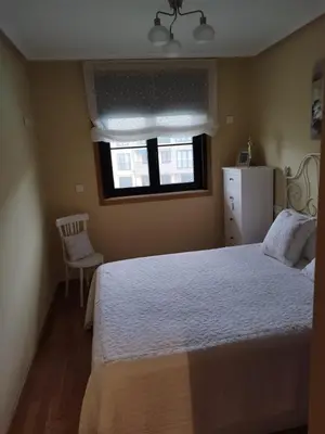 a bedroom with a bed and a window and a chair at COSTA REINANTE SPA Y PISCINA in San Miguel de Reinante